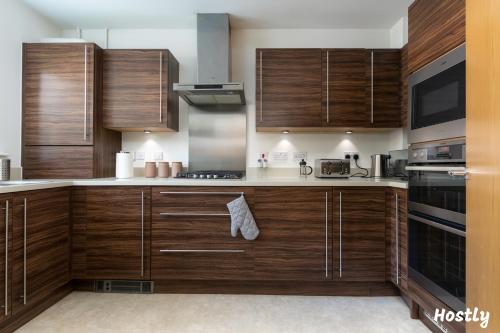 a large kitchen with wooden cabinets and appliances at Albatross House - Comfy Home with Parking in Slough