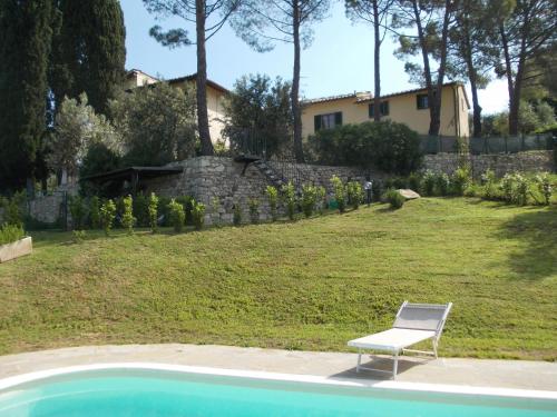 una silla blanca sentada junto a un patio con una casa en Il Palagetto, en Bagno a Ripoli