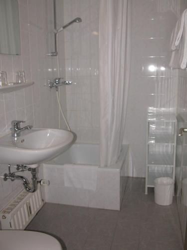a bathroom with a sink and a toilet and a tub at Downtown Vi Vadi Hotel in Munich