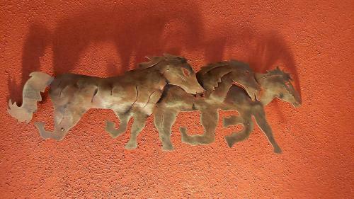 two metal horses on the side of a red wall at Posada Yolihuani in Pátzcuaro