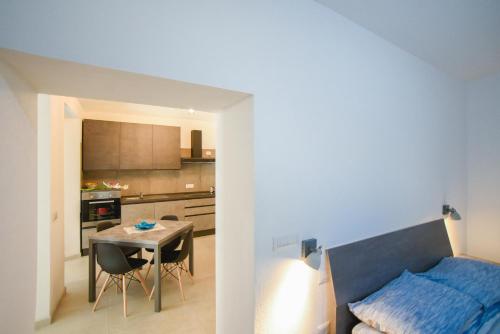 a room with a bed and a table and a kitchen at Tatta & Nanna Apartment in Oliena