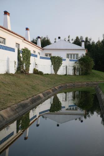 a house and its reflection in a body of water at Apartamentos Canal da Agua in Odeceixe