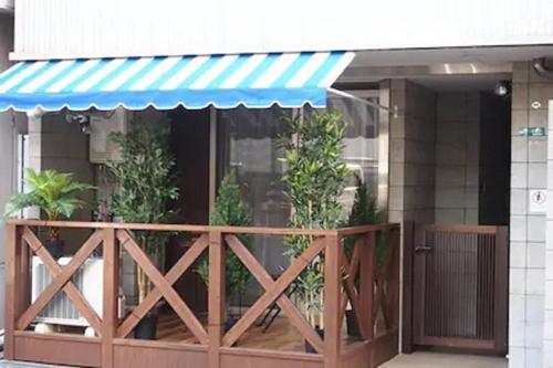 a building with a wooden fence and a blue awning at I Planet Nanba - Vacation STAY 8480 in Osaka