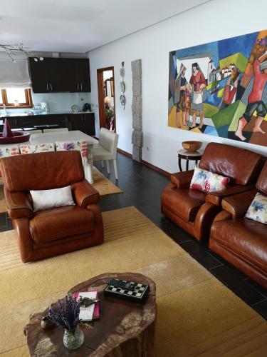 a living room with brown leather furniture and a kitchen at Encosta do Douro - Rio Douro in Cinfães