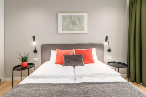 sypialnia z dużym białym łóżkiem z pomarańczowymi poduszkami w obiekcie BellMi Apartamenty - Parking Gratis, Plaża 5min, Komfort i Relaks w Kołobrzegu