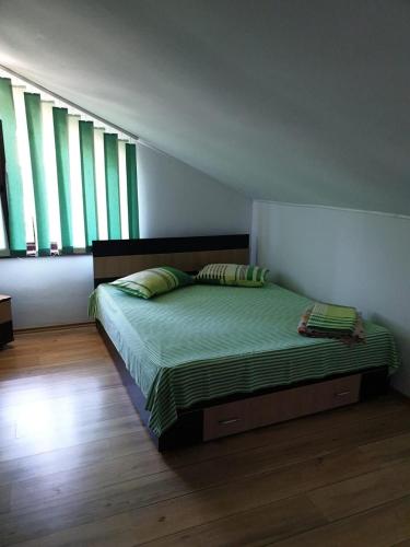 a bedroom with a bed with green sheets and windows at Casa di Madi in 2 Mai