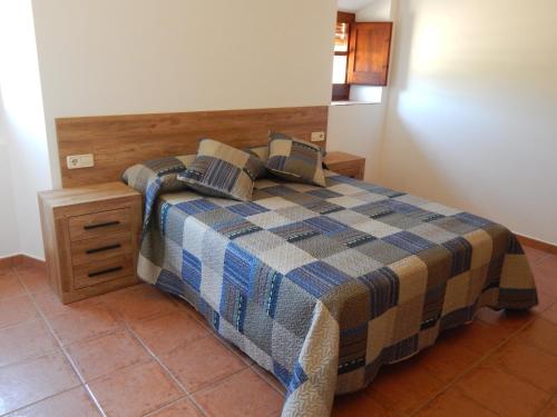 a bedroom with a bed with a plaid blanket at Masia Lledó de Trascastell in Balsareny