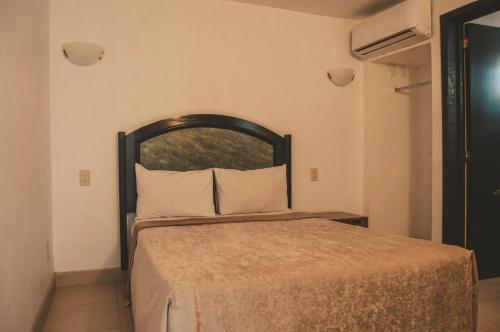 a bed with a wooden headboard in a room at Hotel Latino in Guadalajara