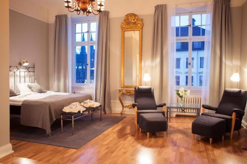1 Schlafzimmer mit einem Bett, 2 Stühlen und einem Spiegel in der Unterkunft Grand Hotell Hörnan in Uppsala