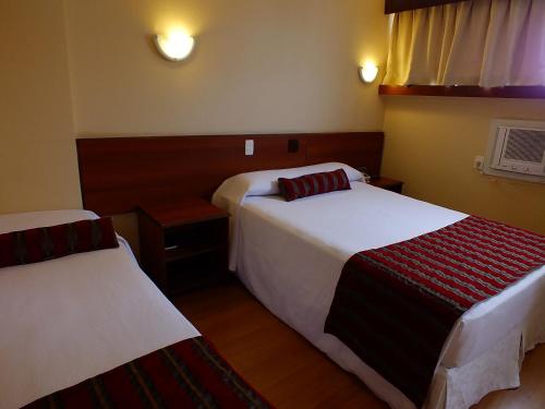 a hotel room with two beds and a window at Hotel Nacional Inn Curitiba Estação Shopping in Curitiba