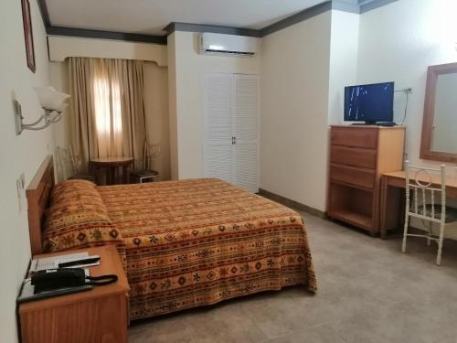 una camera d'albergo con letto, scrivania e TV di Hotel Astromundo a Reynosa