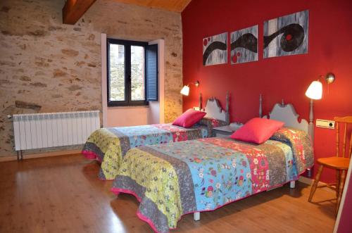 two beds in a room with red walls at Casa Fonte do Barro SPA opcional in Santiago de Compostela