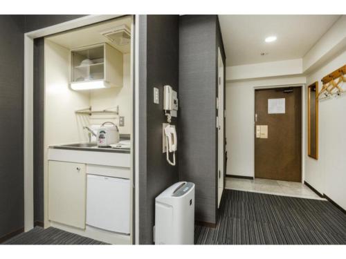 uma pequena cozinha com um lavatório e uma lata de lixo em HOTEL MYSTAYS Otemae - Vacation STAY 87137 em Osaka