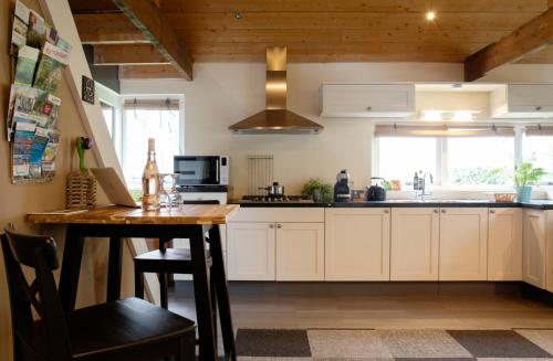 a kitchen with white cabinets and a wooden table at Buitenverblijf Het Grootenhuis in Winterswijk Henxel