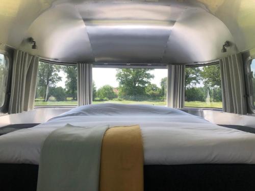 Amerikaanse Airstream voor 2 personen في Reutum: غرفة نوم مع سرير أبيض كبير مع نوافذ