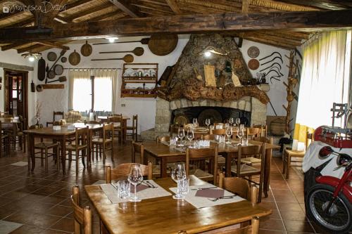 un ristorante con tavoli in legno e un camino in pietra di Affittcamere Jannas a Orgosolo