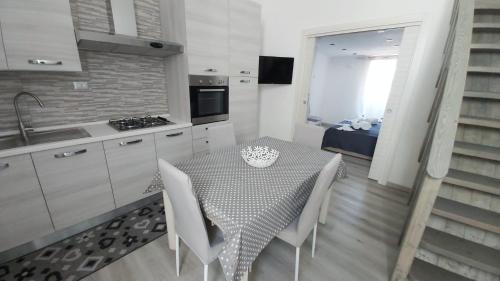 una cucina con tavolo, sedie bianche e lavandino di Case Vacanze Porto Vecchio a Lampedusa