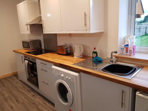 a kitchen with a sink and a washing machine at Pleasant Point Holiday Cottages in Rosemarkie