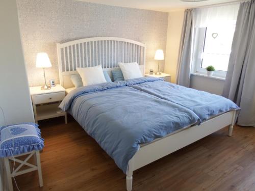 1 dormitorio con 1 cama grande y edredón azul en Ferienwohnung Seestern, en Wangerland
