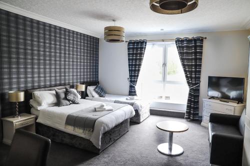 1 dormitorio con cama, sofá y TV en Ardennan House Hotel en Inverurie