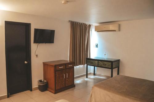 ein Hotelzimmer mit einem Schreibtisch und einem TV an der Wand in der Unterkunft Hotel Latino in Guadalajara
