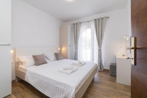 Un dormitorio blanco con una cama grande y una ventana en MALOA two bedroom apartment, en Smokvica