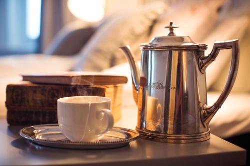 a coffee pot and a cup on a table at Grand Hotell Hörnan in Uppsala