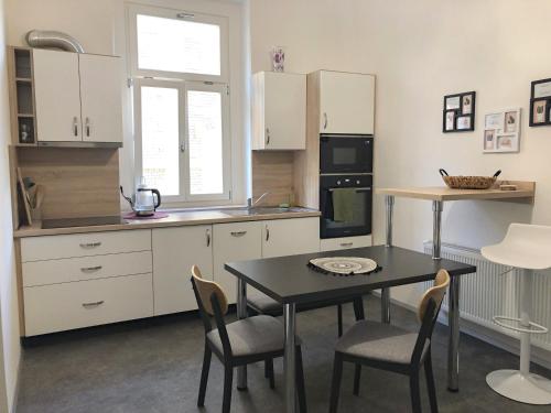 uma cozinha com mesa e cadeiras e uma cozinha com armários brancos em MARIEN Apartment em Mariánské Lázně