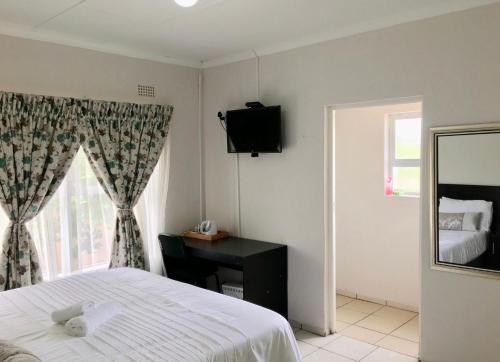 Schlafzimmer mit einem Bett, einem Schreibtisch und einem Fenster in der Unterkunft White House lodge in Mthatha