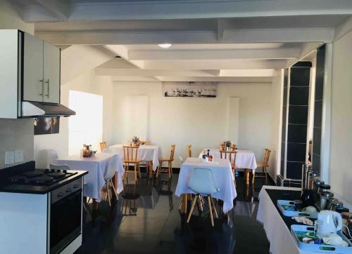 a kitchen with two tables with white table cloth at White House lodge in Mthatha