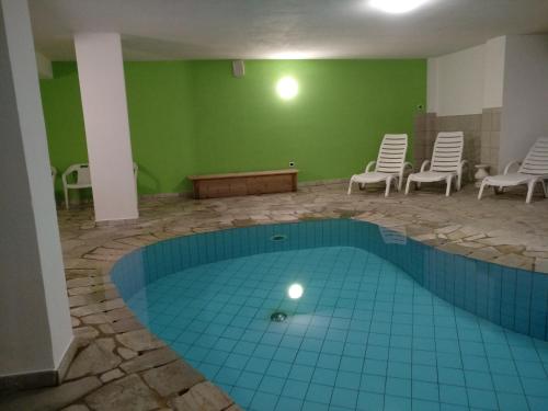 a swimming pool in a room with chairs around it at Hotel Rainhof in Senales
