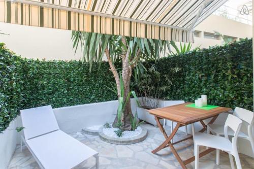 a patio with a table and chairs and a palm tree at CENTRE PROMENADE With terrace next to the sea in the pedestrian area in Nice