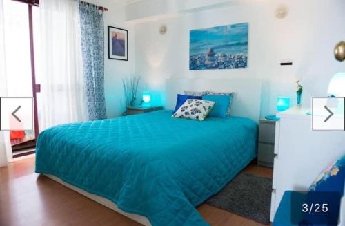 a blue bedroom with a bed and a window at Casa da Piscina in Sesimbra
