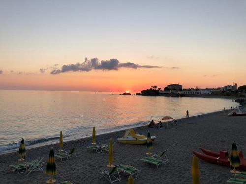a beach with chairs and umbrellas at sunset at La Risacca Relais in Belvedere Marittimo