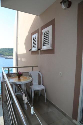 a balcony with a table and a white chair at Apartments Dragica in Milna