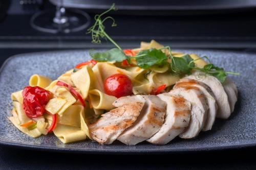 a plate of food with meat and pasta on a table at Hotel Cool Zagreb Airport in Velika Gorica