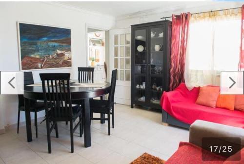 a living room with a table and a red couch at Casa da Piscina in Sesimbra