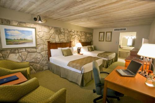a hotel room with two beds and a desk at Inn of the Hills Hotel and Conference Center in Kerrville