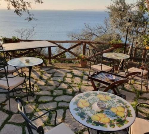 a patio with tables and chairs next to the ocean at La Palombara B&B in Vico Equense