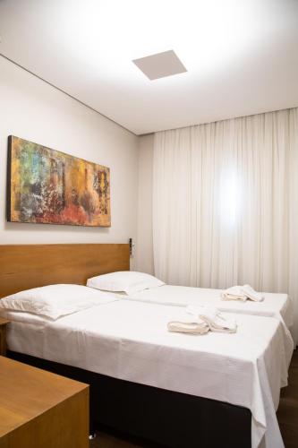 a bedroom with two beds and a painting on the wall at ESPAÇO 250 - Apto mobiliado, 3 quartos, sendo uma suíte, banheiro social, cozinha completa, sala de estar, ar condicionado, tv e internet in Tiradentes