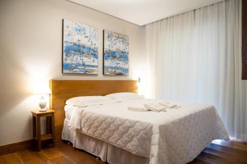una camera da letto con un letto bianco con due asciugamani di ESPAÇO 250 - Apto mobiliado, 3 quartos, sendo uma suíte, banheiro social, cozinha completa, sala de estar, ar condicionado, tv e internet a Tiradentes