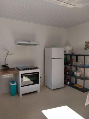 a kitchen with a white refrigerator and a stove at Refúgio das Araucárias in Ibiúna