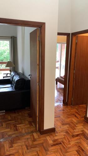 a living room with a black couch and a wooden floor at Refúgio das Araucárias in Ibiúna