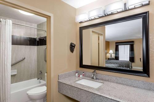 a bathroom with a sink and a toilet and a mirror at Days Inn by Wyndham Sarasota Bay in Sarasota