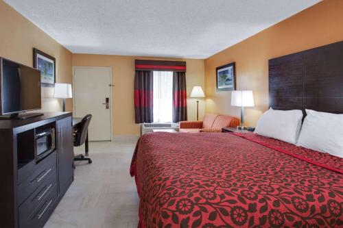 a hotel room with a red bed and a television at Days Inn by Wyndham Sarasota Bay in Sarasota