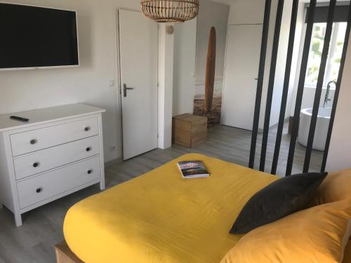 a bedroom with a bed and a dresser with a tv at Etoile du Kap in Barneville-Carteret