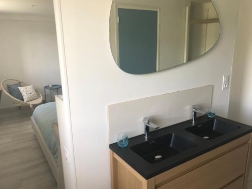 een badkamer met een zwarte wastafel en een spiegel bij Etoile du Kap in Barneville-Carteret