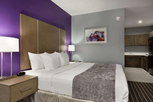 a hotel room with a large bed and purple walls at Days Inn by Wyndham Odessa in Odessa