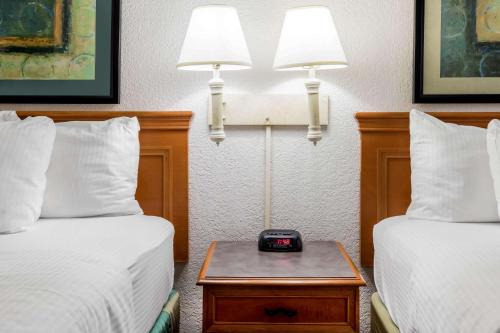 a hotel room with two beds and a clock on a table at La Quinta Inn by Wyndham Lufkin in Lufkin