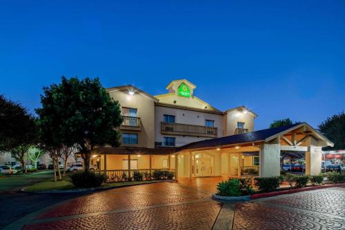 La Quinta Inn & Suites by Wyndham Irvine Spectrum في ايرفين: مبنى فندقي وساعة خضراء فوقه